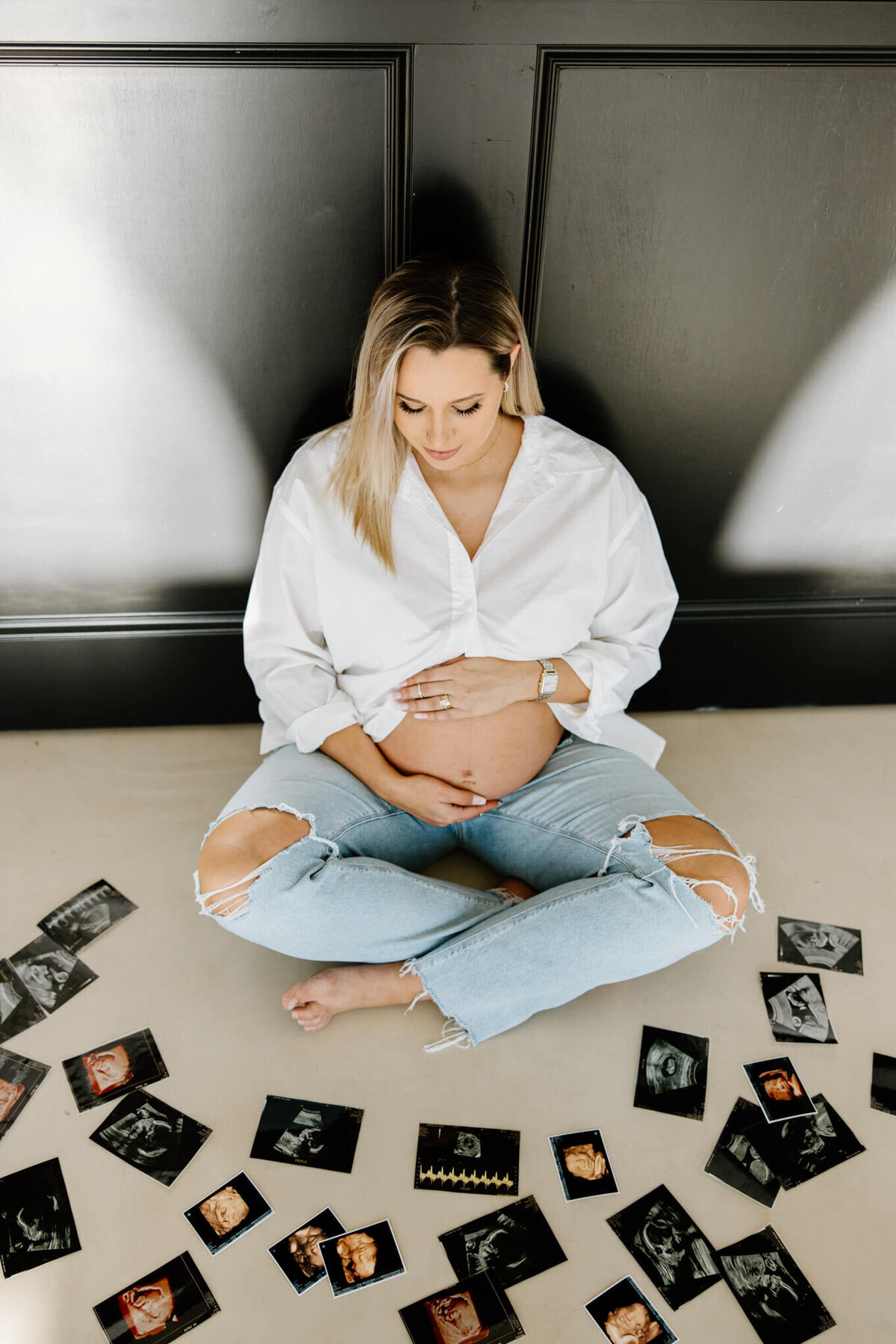 expecting mother in white shirt and jeans looking through sonogram pics