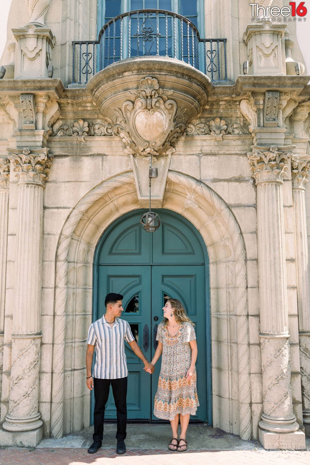 Engaged couple hold hands and look at each other during engagement shoot