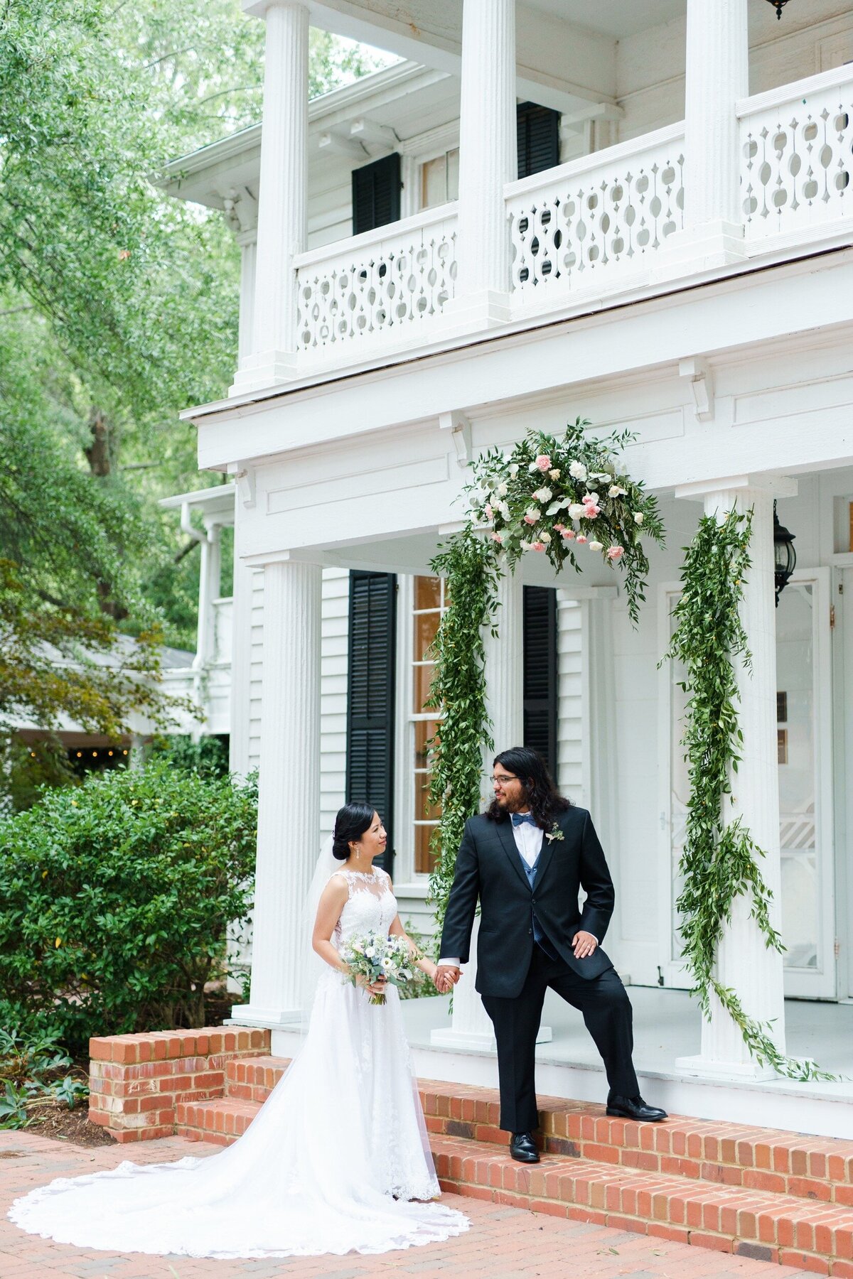 Groom leads his bride up the steps of the Leslie Alford Mims House Raleigh wedding venue.