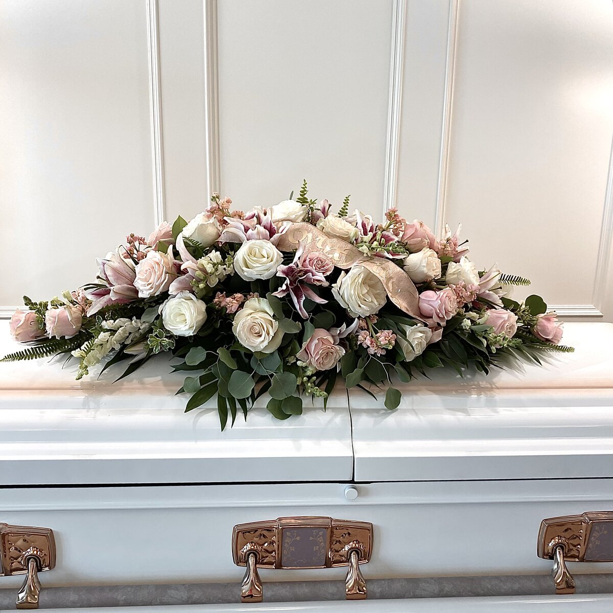 pink and white funeral casket spray with loving mother on the ribbon