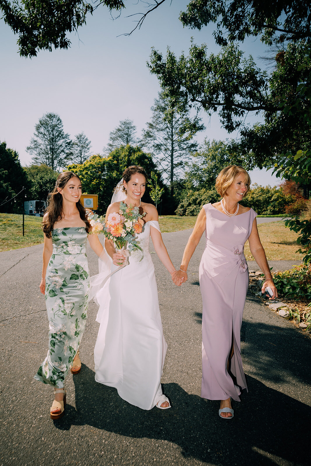A bride walks hand in hand with her mother and sister