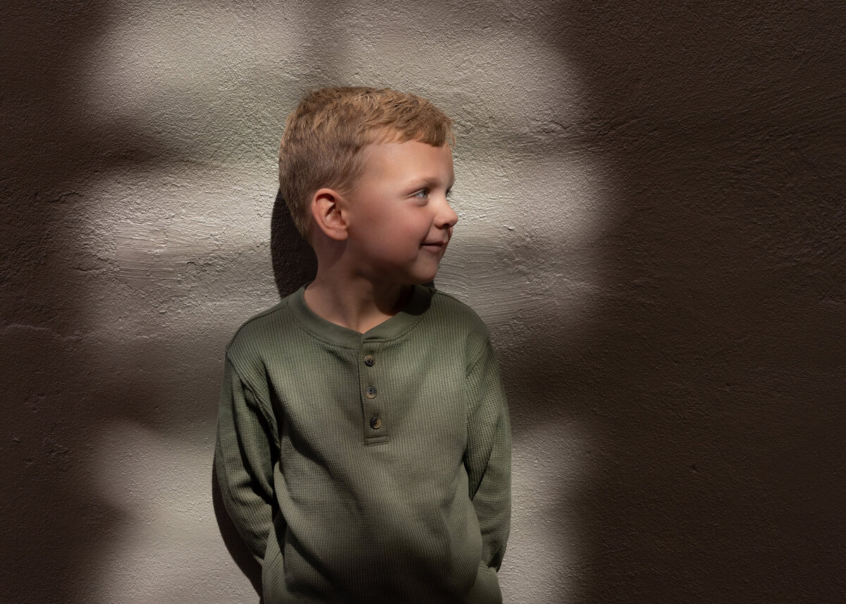 A single sunbeam illuminates a child's face in a dimly lit alleyway.
