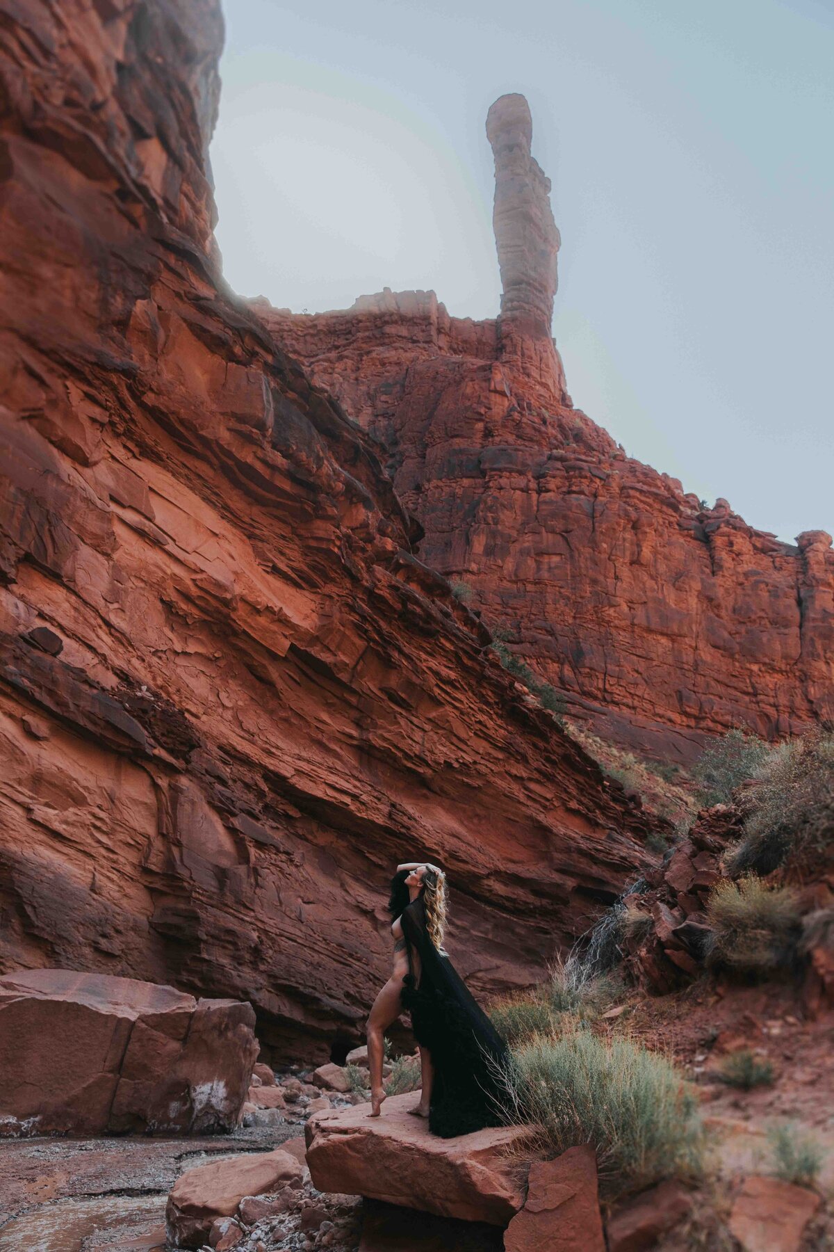 Woman posing in a desert canyon wearing only a robe