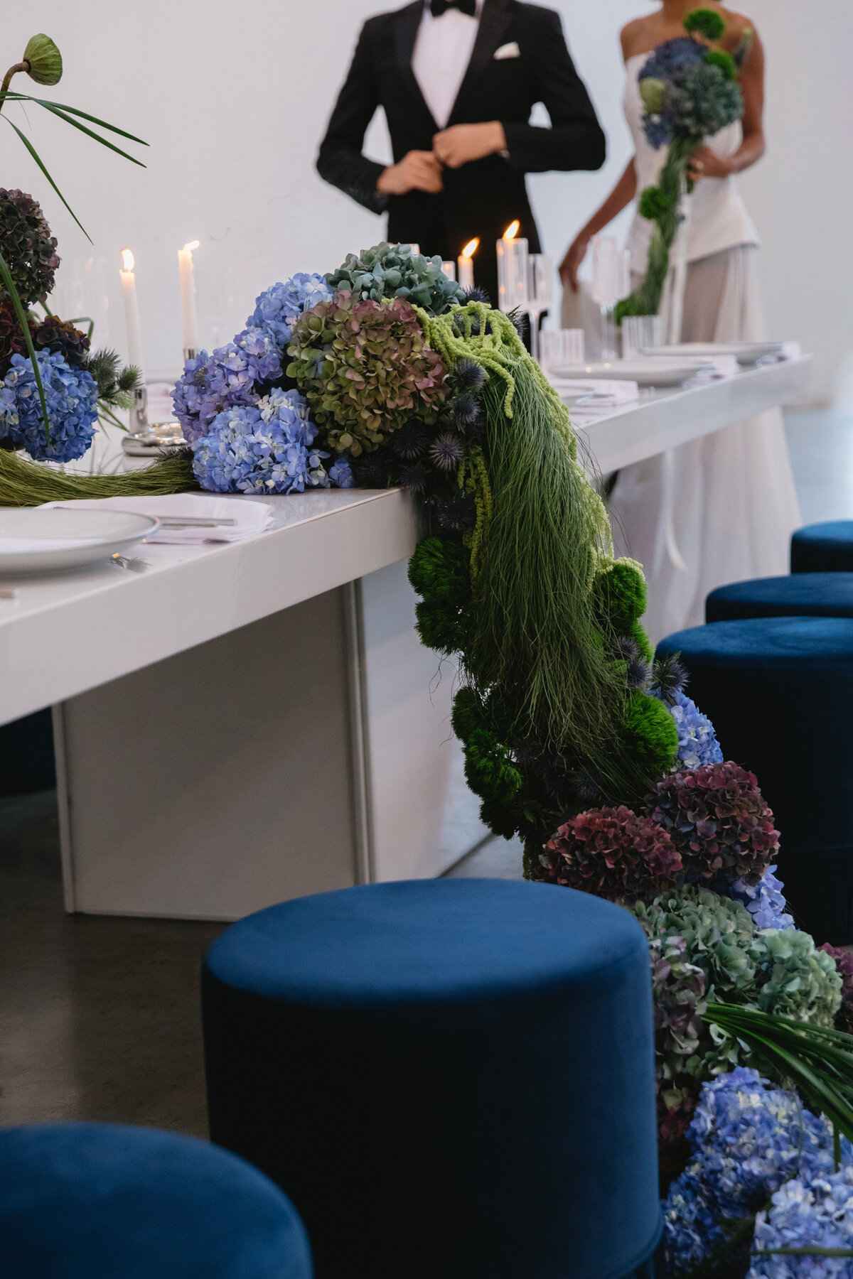 Artistic floral installation with hydrangeas and greenery draped along a modern wedding table.