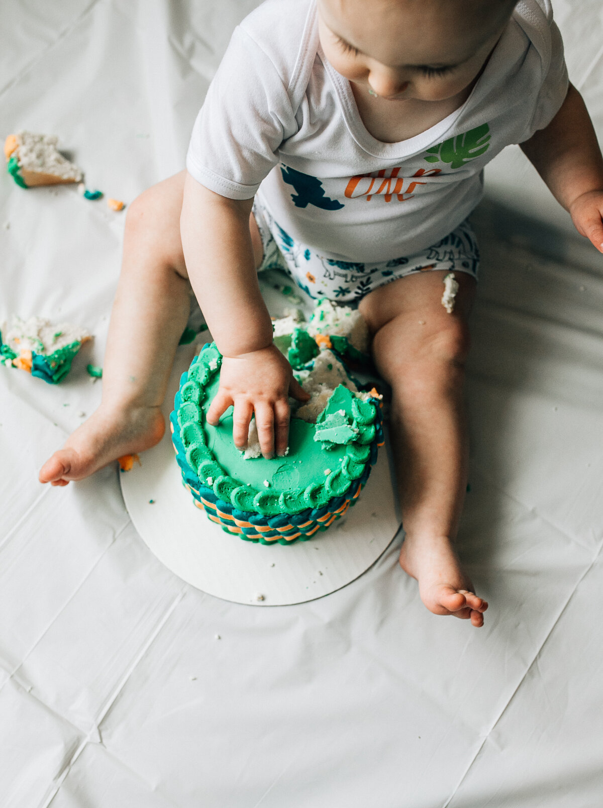 Baby sits on the floor with cake.