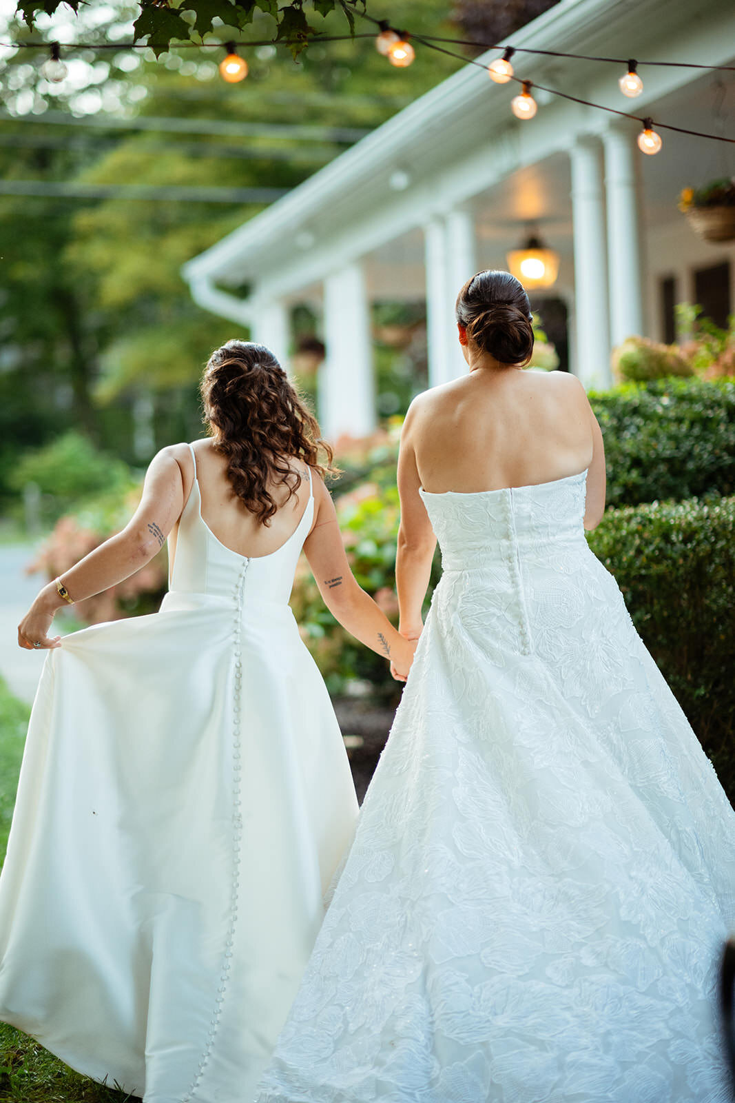 Two brides holding hands walking away from camera