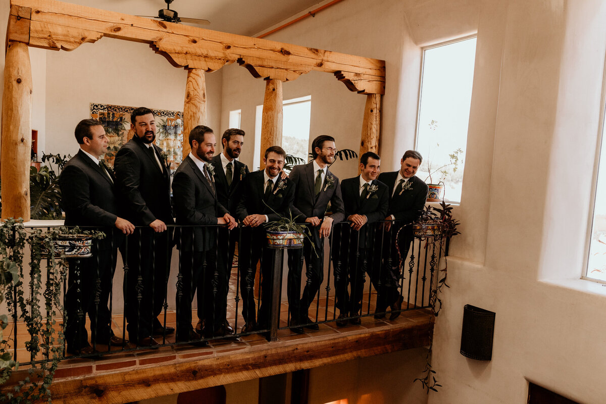 groom hanging out with groomsmen on a balcony