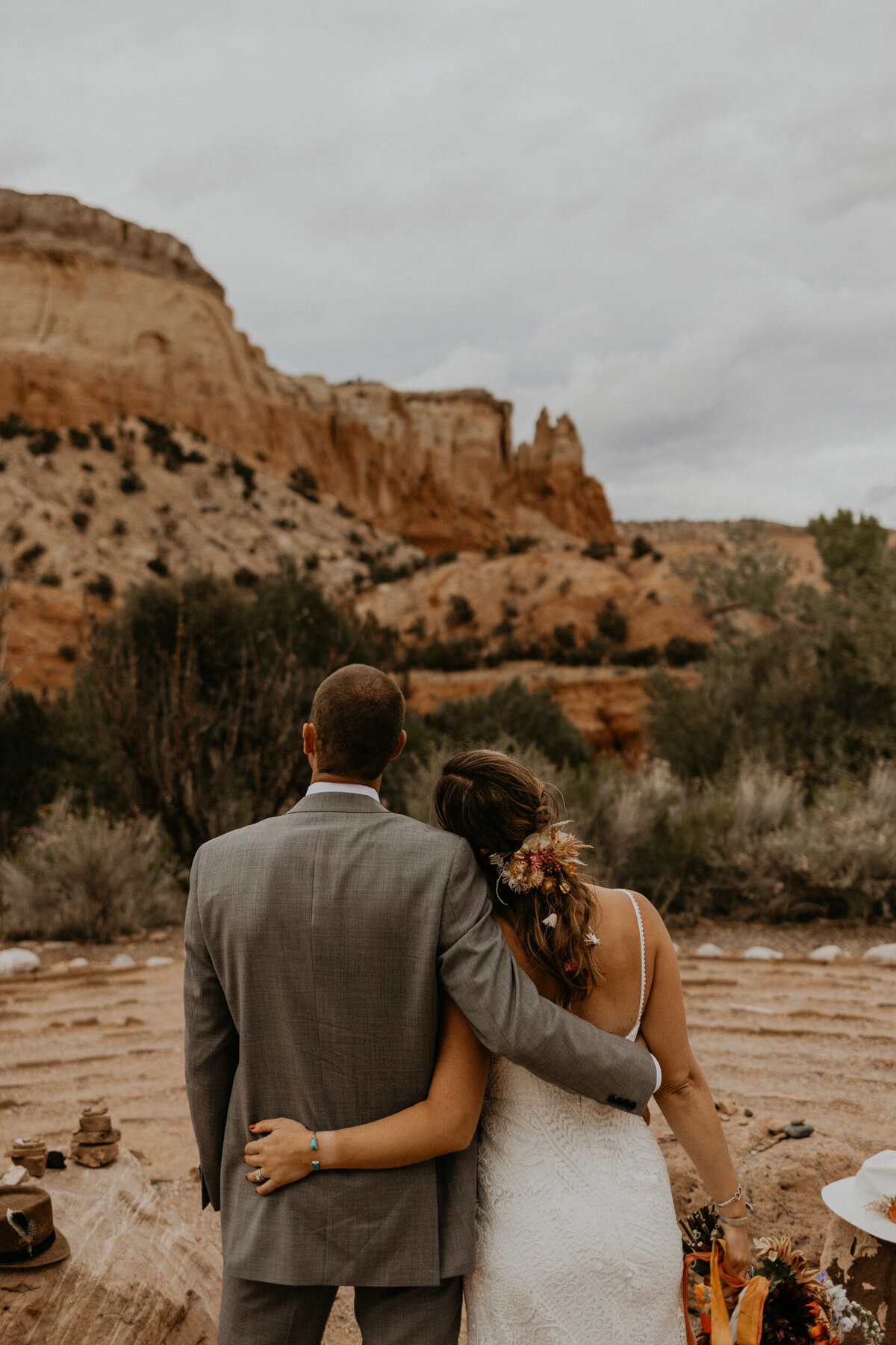 bride and groom looking away at red rocks in Abiquiu NM