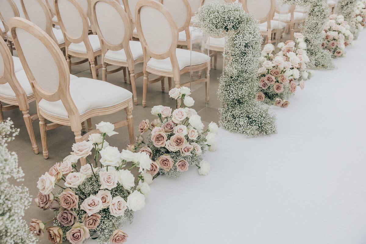 Elegant white and dusty pink roses lining  luxurious wedding aisle