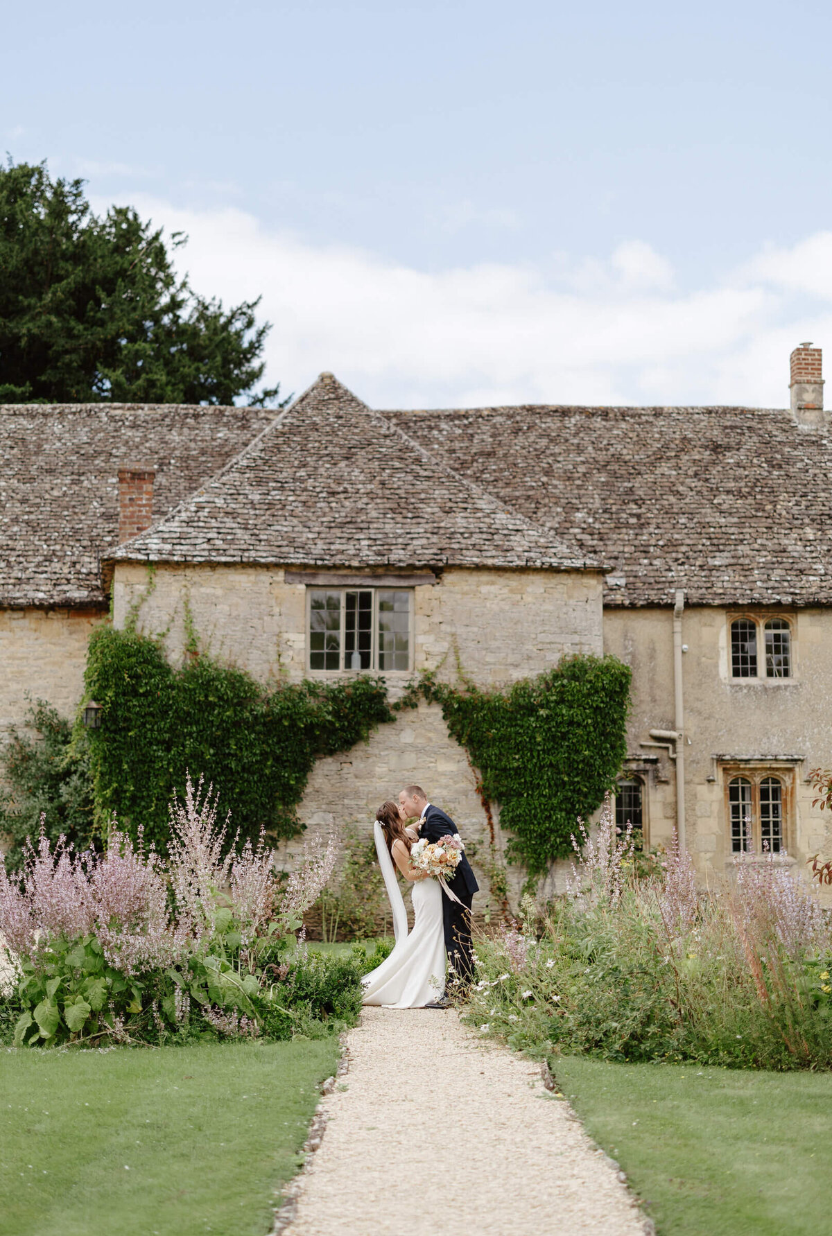 Bride and groom in the perfectly English country gardens at Caswell House, surrounded by flowers