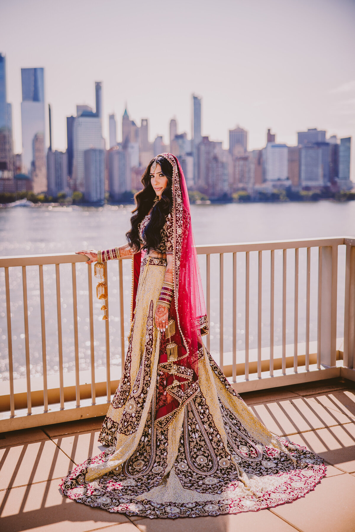 Indian bride against the balcony in front of the nyc skyline at the jersey city hyatt on the wedding