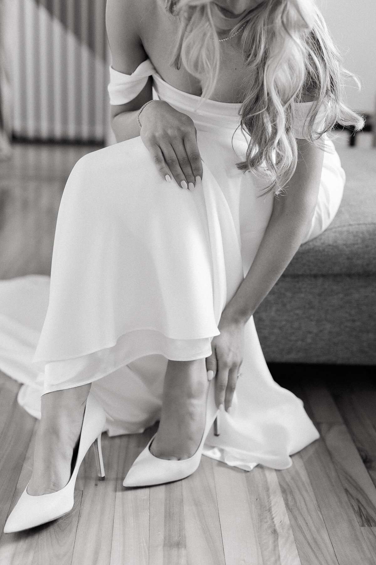 Une mariée met ses souliers de mariage. 