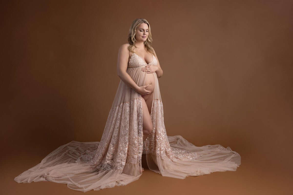 pregnant woman in flowy dress with her hands  on her belly