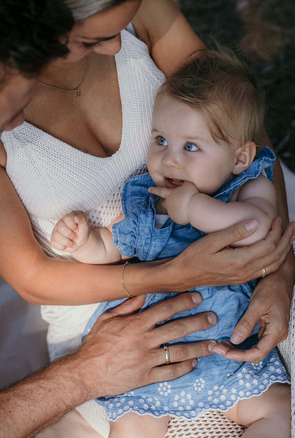 Closeup of babygirl in a blue dress looking at her dad during a family session