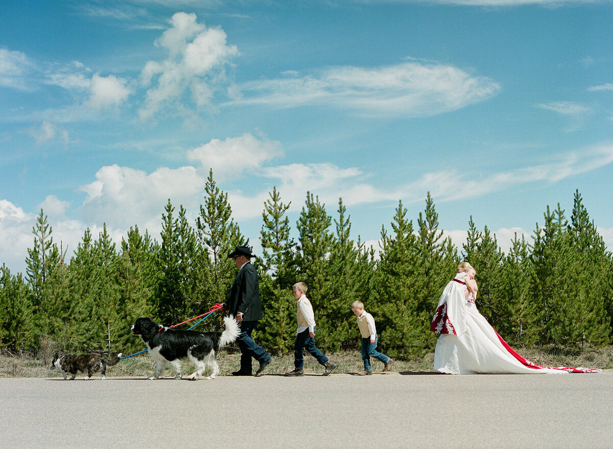 family walks in a line in front of pine trees