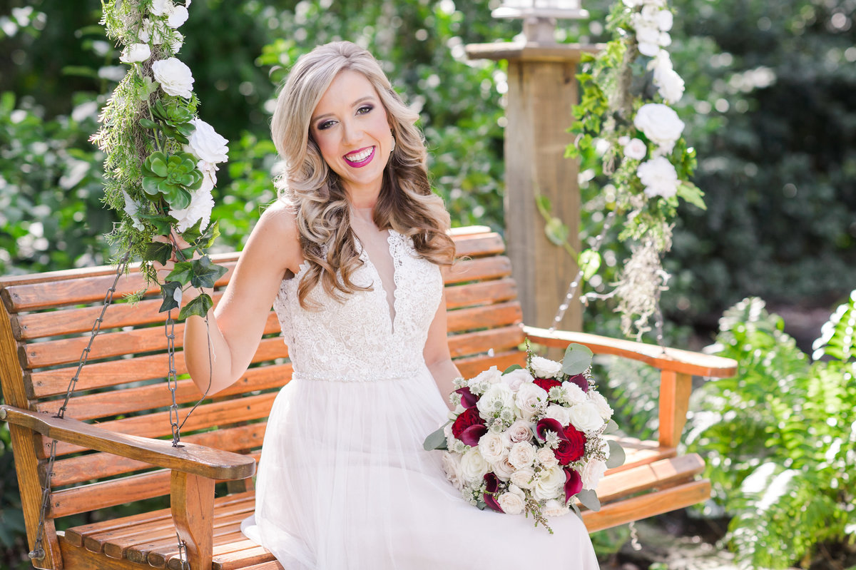 Bride holding her bouquet on a bench swing before her wedding at Bakers Ranch
