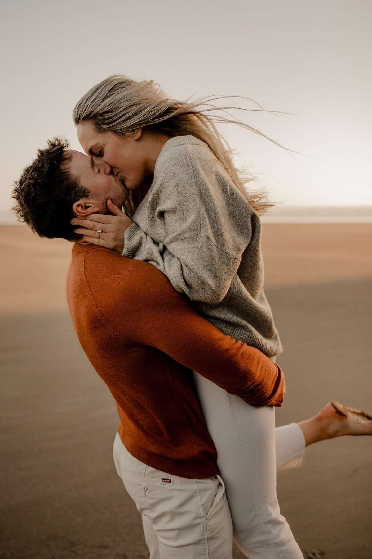Couple embraces on a beach at sunset in Oregon