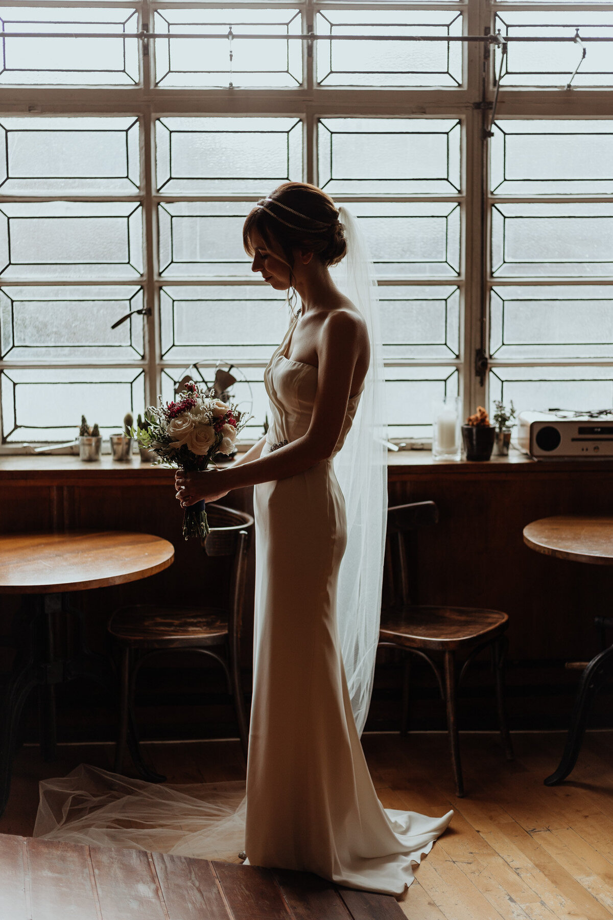 bride with bouquet standing by window