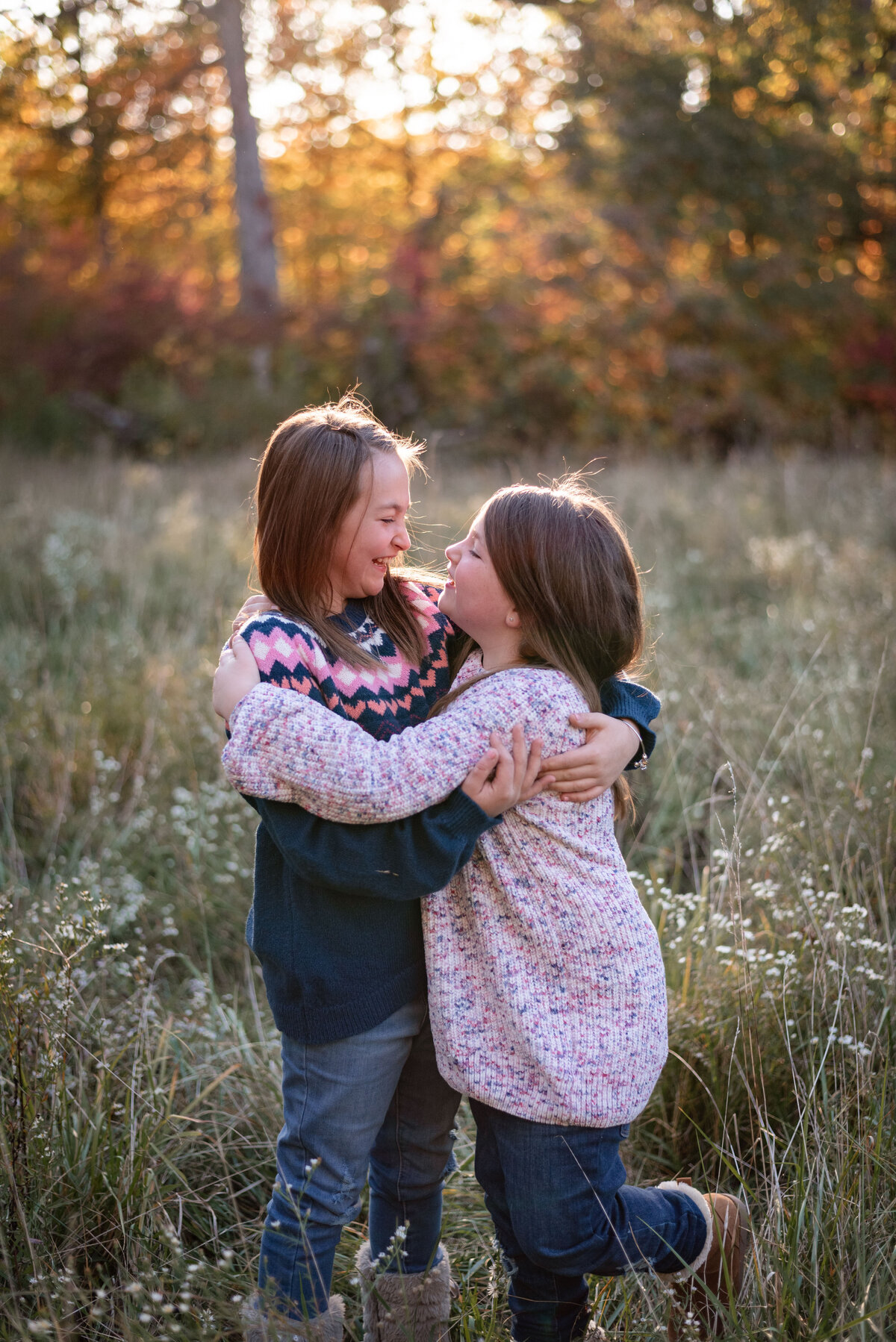 loving sisters laughing in meadow in wells county family photographer northeast indiana