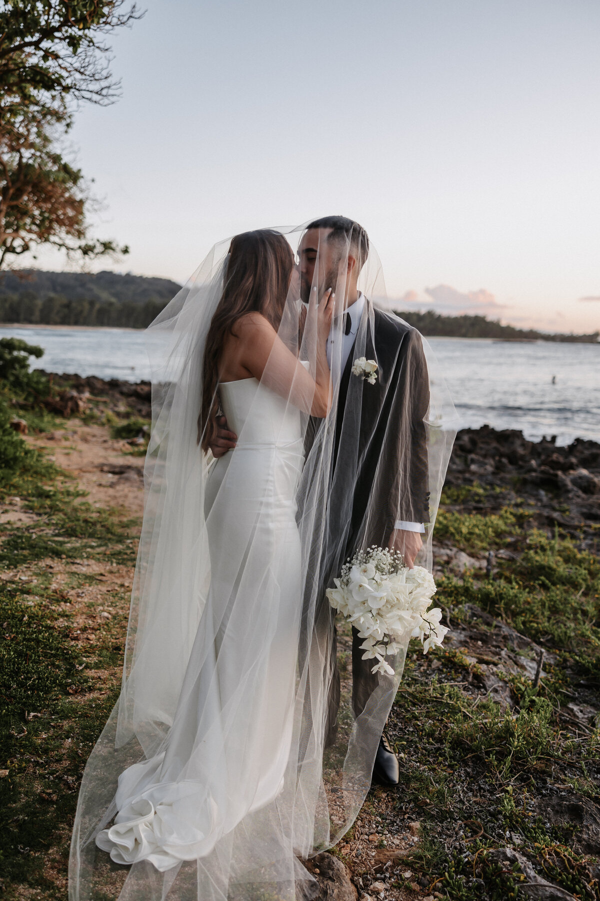 Elopement Photography, couple kisses under veil with the ocean next to them