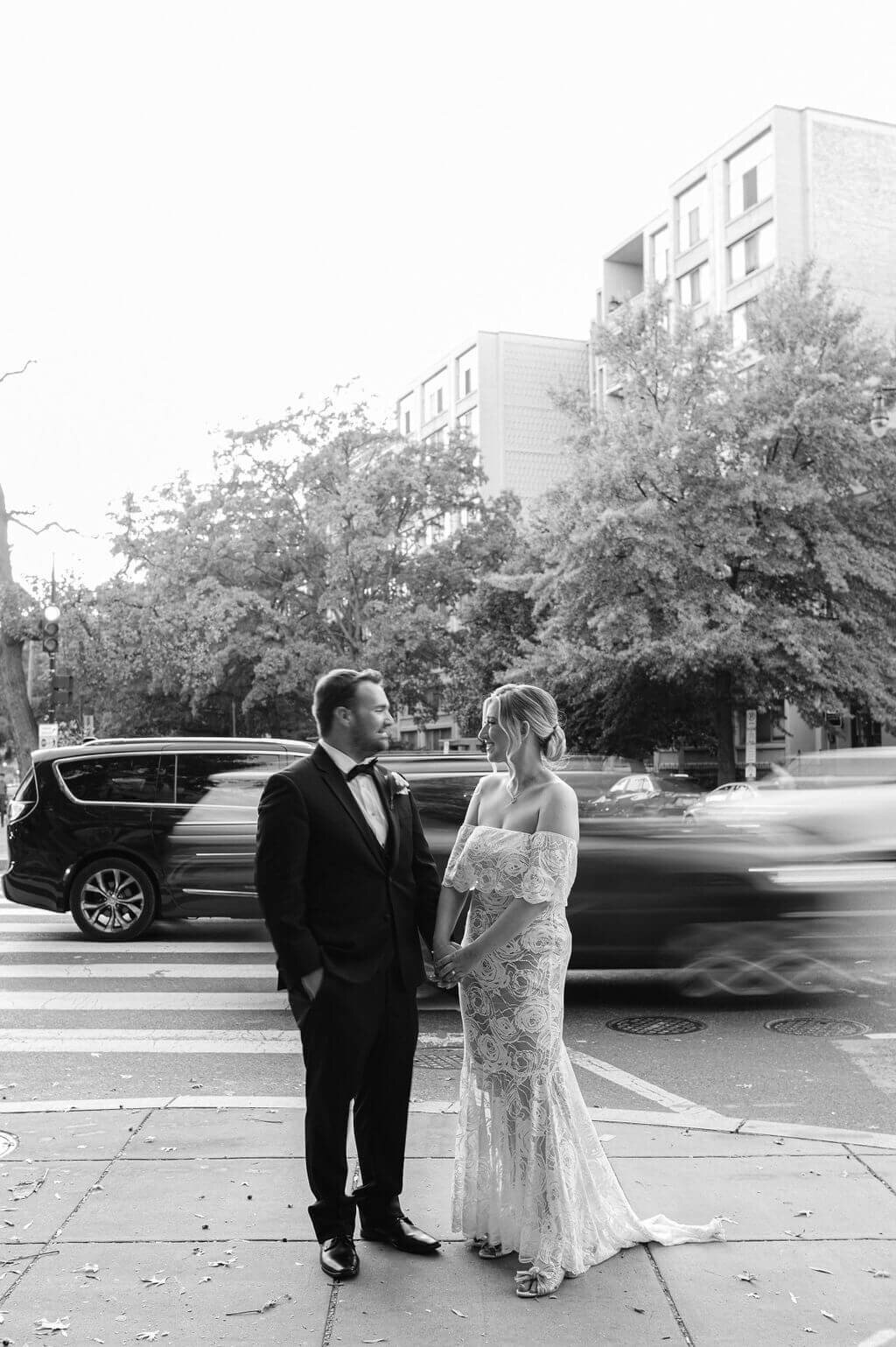 Motion blur image of a bride and groom holding hands as cars drive by them during their wedding photos in DC