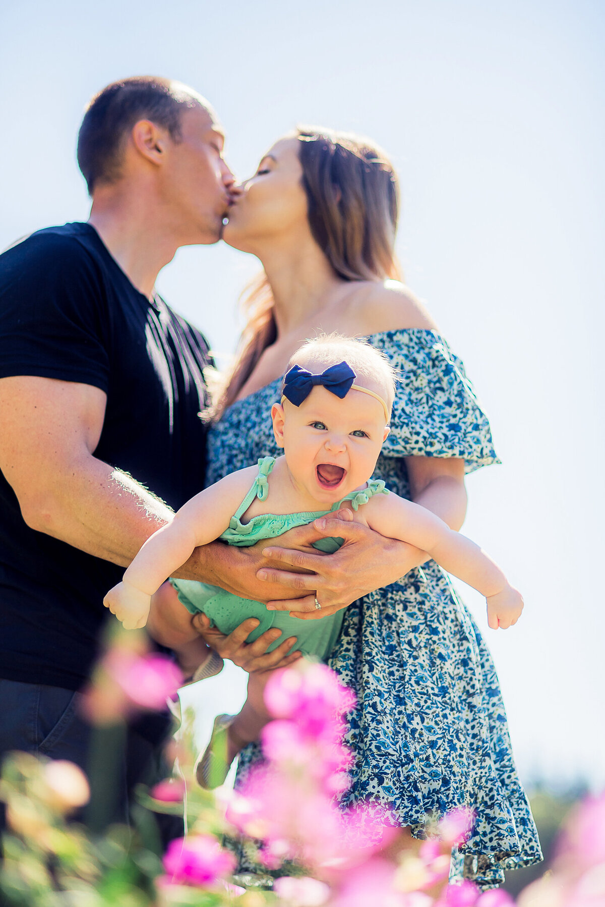 couple kissing with baby girl smiling
