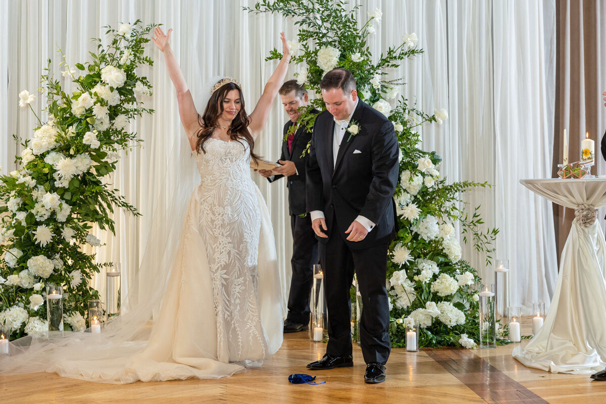 A bride and groom are celebrating their wedding with their arms in the air