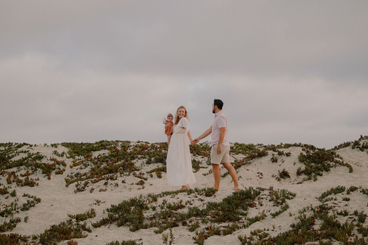 Couple walking together on a dune with their baby