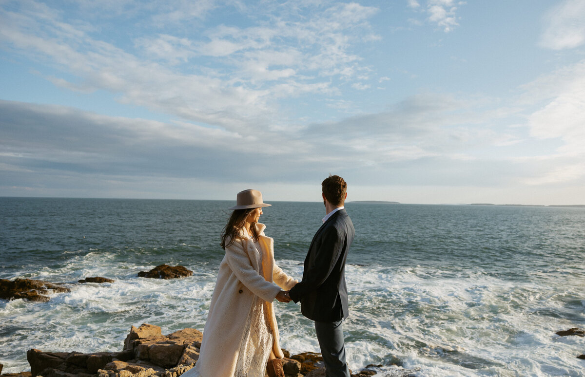 Couple holding hands at their Otter Point elopement in Acadia National Park