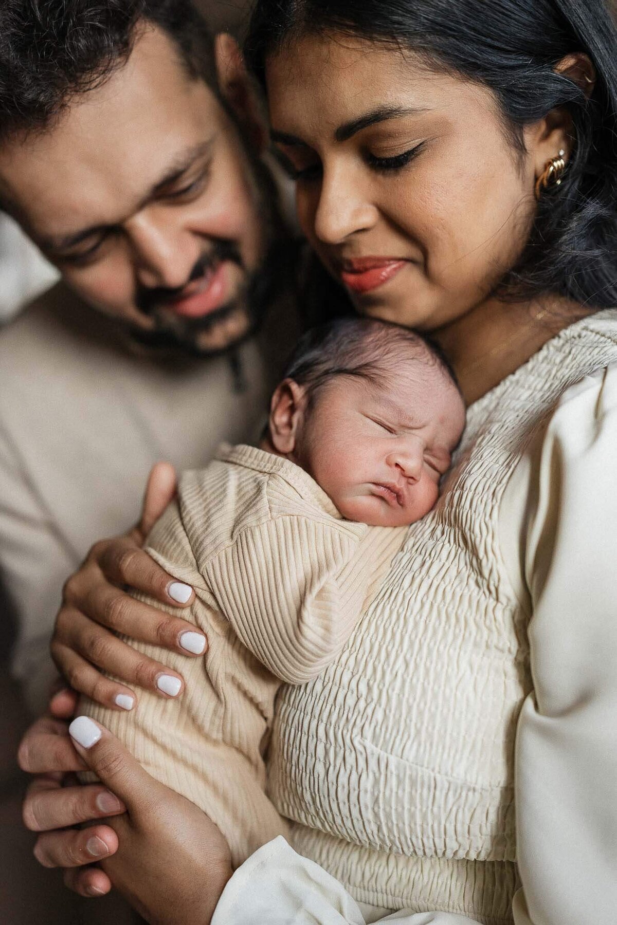 A close-up of parents holding sleeping newborn son during lifestyle photography session in Cleveland.