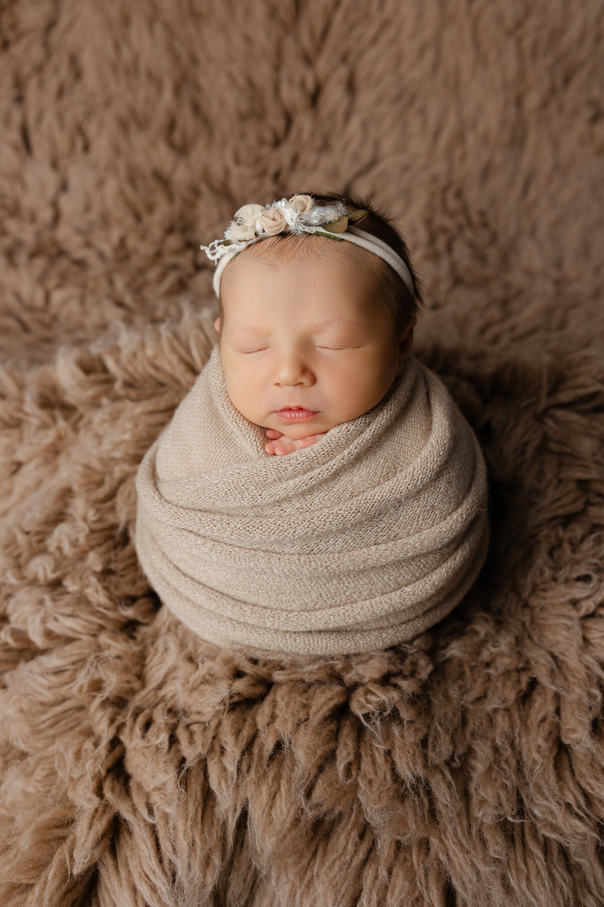 Earthy newborn portrait featuring a sleeping baby girl in beige, styled with soft fur textures and natural tones. Captured by Inland Empire newborn photographer Kaitlyn Dawn.