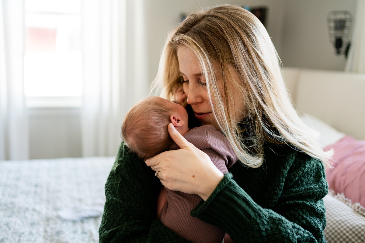 Mom cradling new baby in bedroom