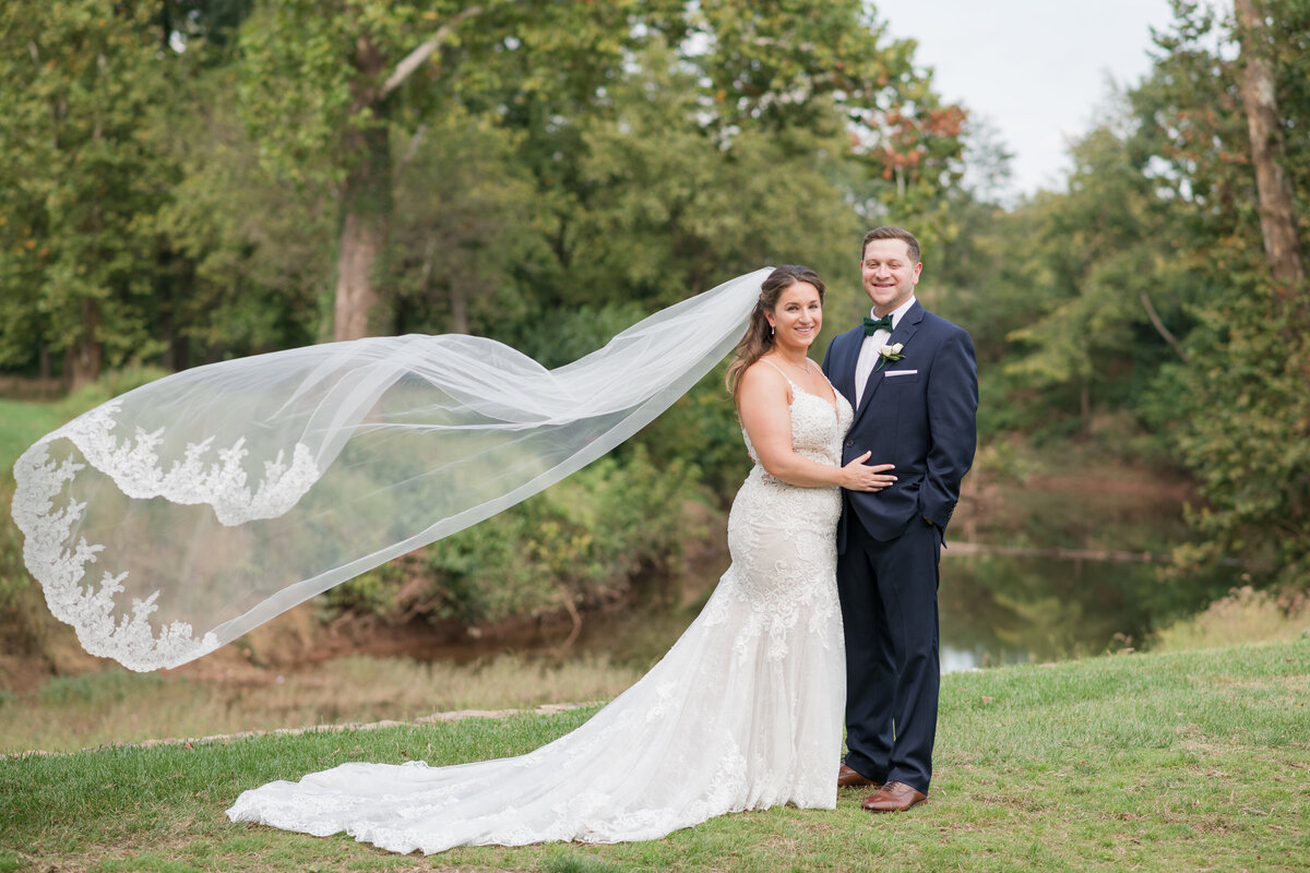 Bride's veil flying in the wind  as she stands with her husband for jewish wedding in Dullus virginia
