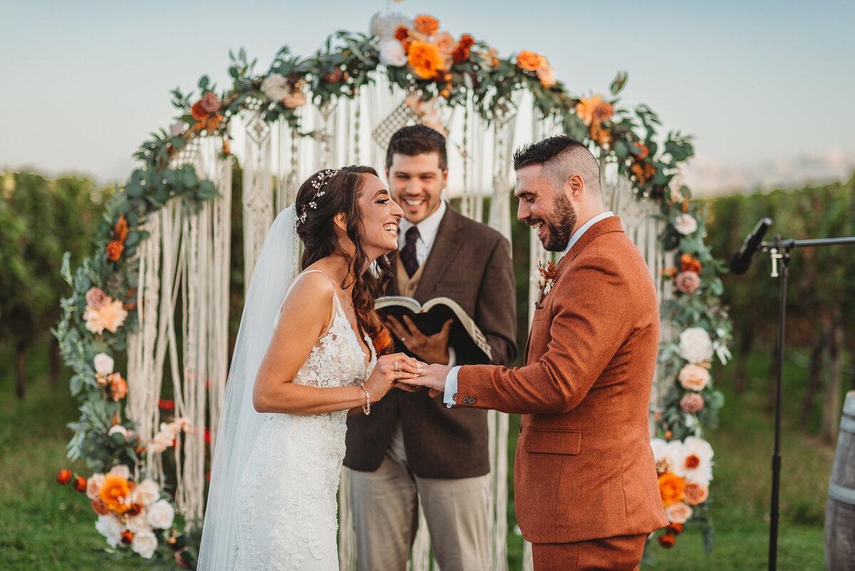 bride placing ring on grooms finger during wedding ceremony