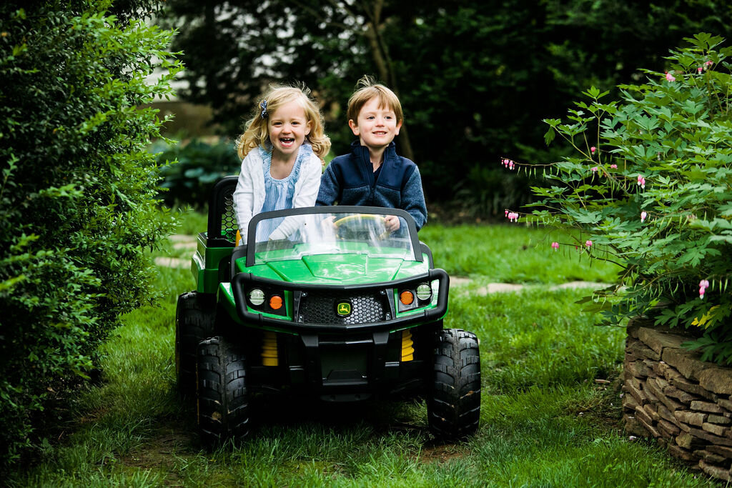 Two kids ride in a small green car.