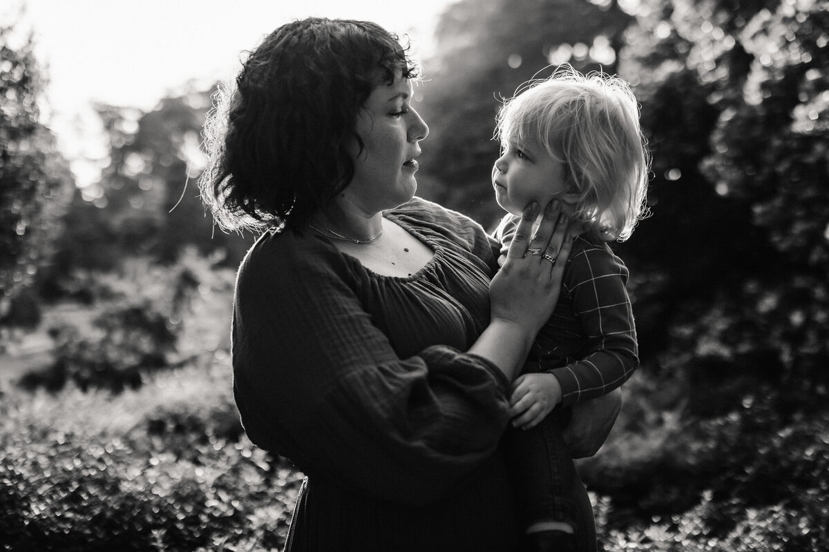 Black and white intimate mother and daughter portrait gazing at one another and mom touches child's cheek
