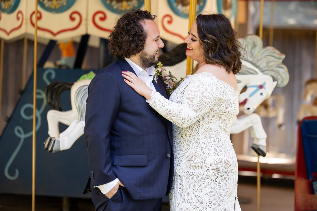 A bride and groom with their arms around each other smiling