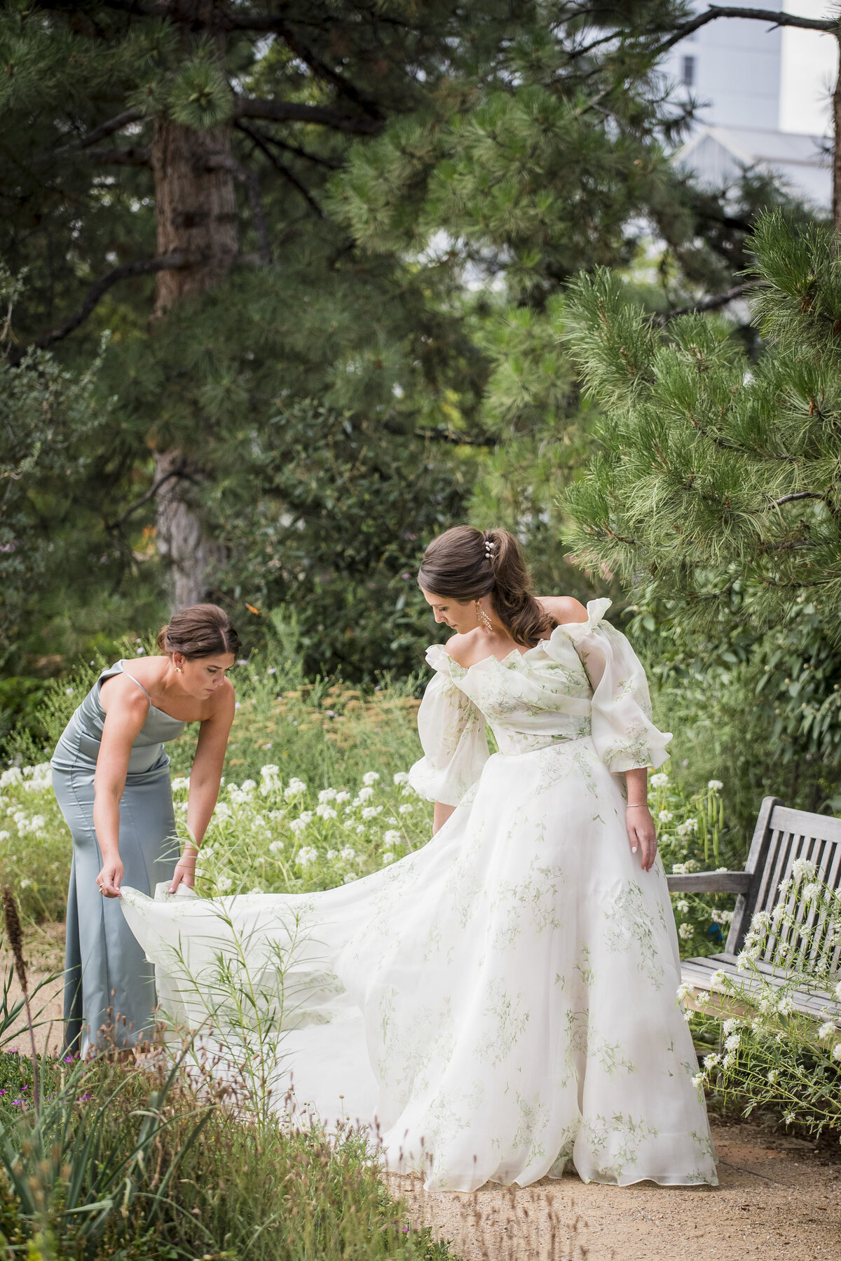 A bridesmaid adjusts the bride's dress train as she gets ready for her first look on her wedding day.