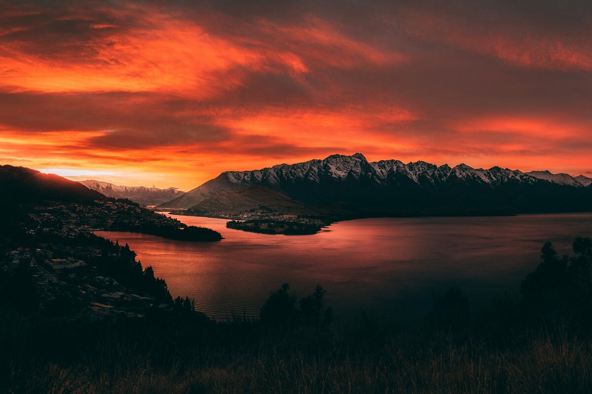 A fiery red sunrise coming up over Queenstown's mountains and lake.