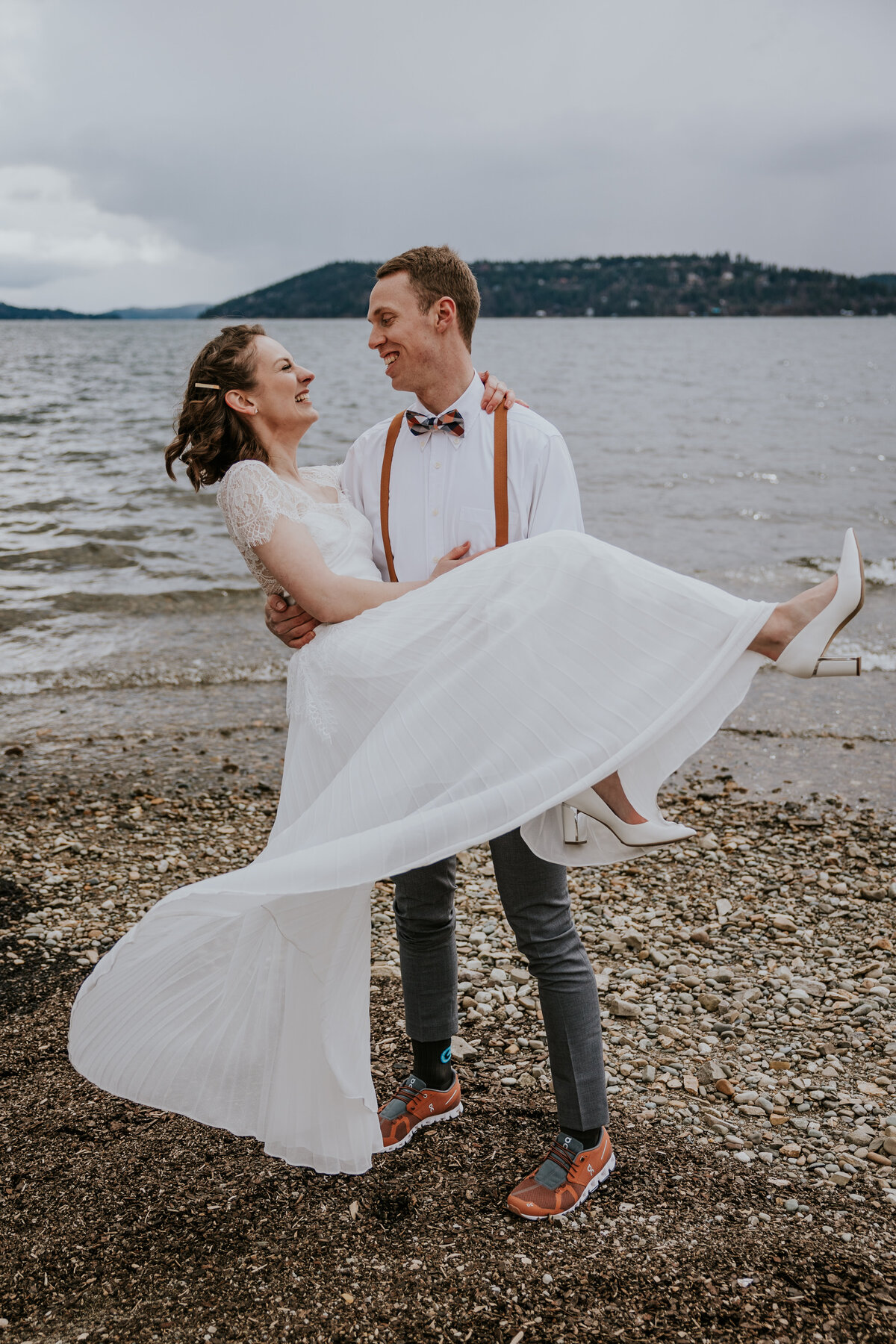 Groom holds bride while her dress blows in the wind.