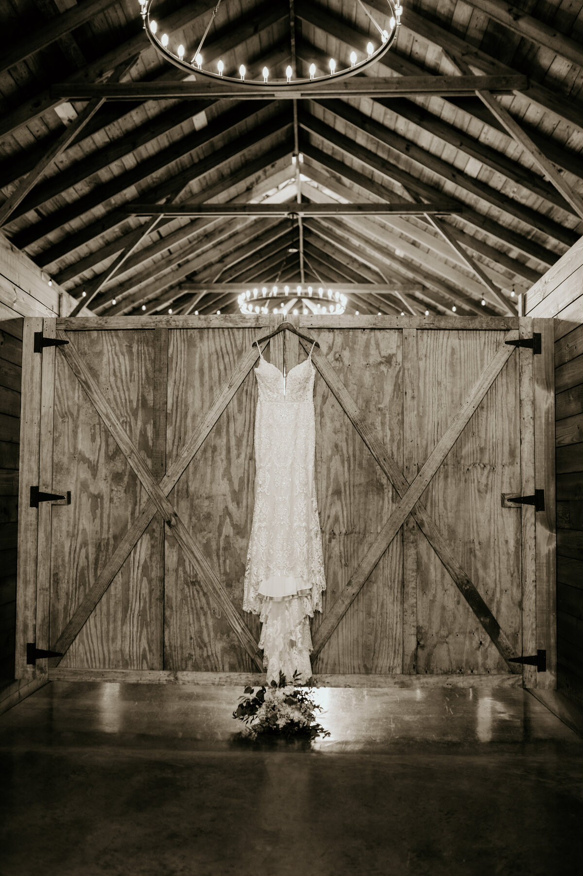 brides wedding dress hanging on a barns door at little rock ar wedding venue