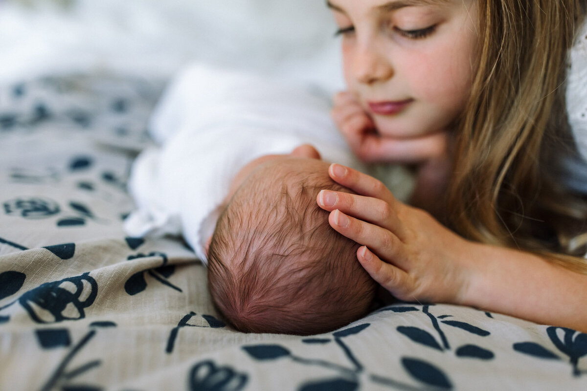 sister-touching-newborn-head