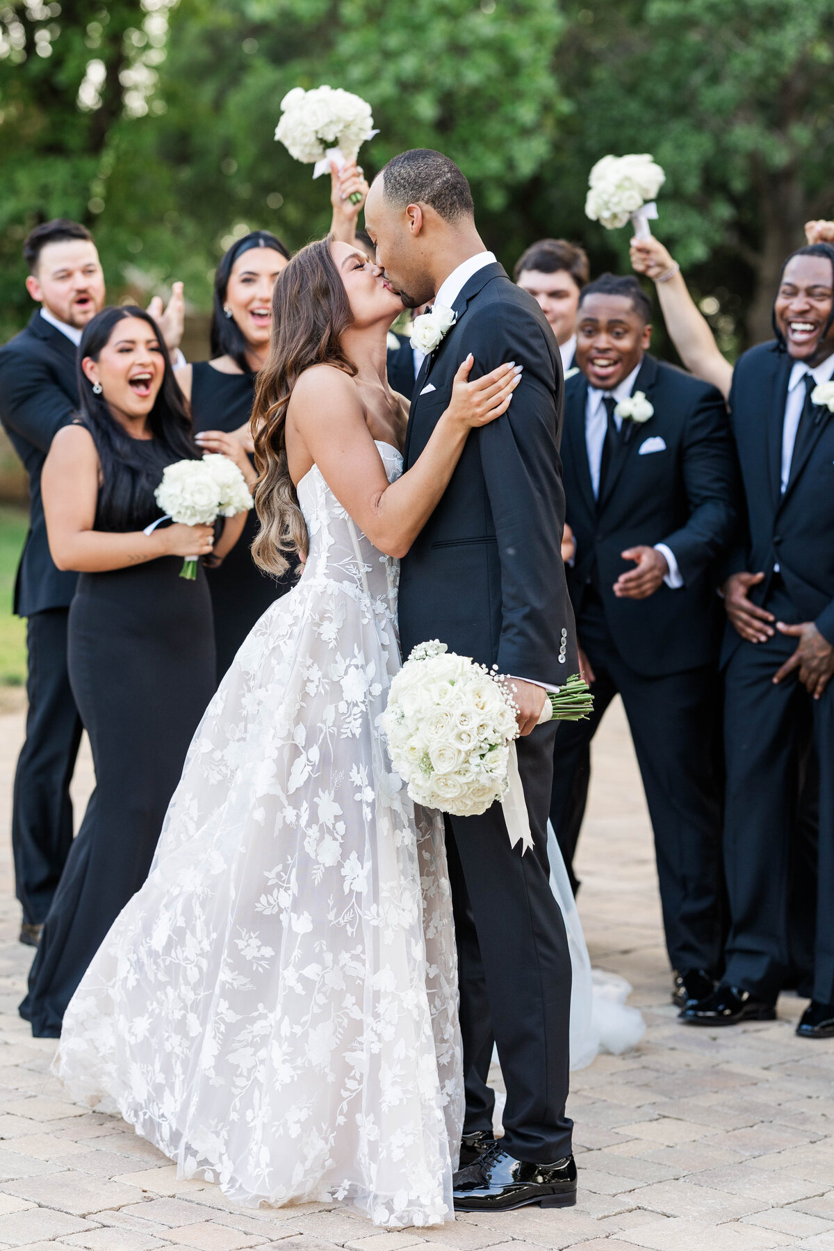 wedding-party-celebrating-as-couple-share-a-first-kiss