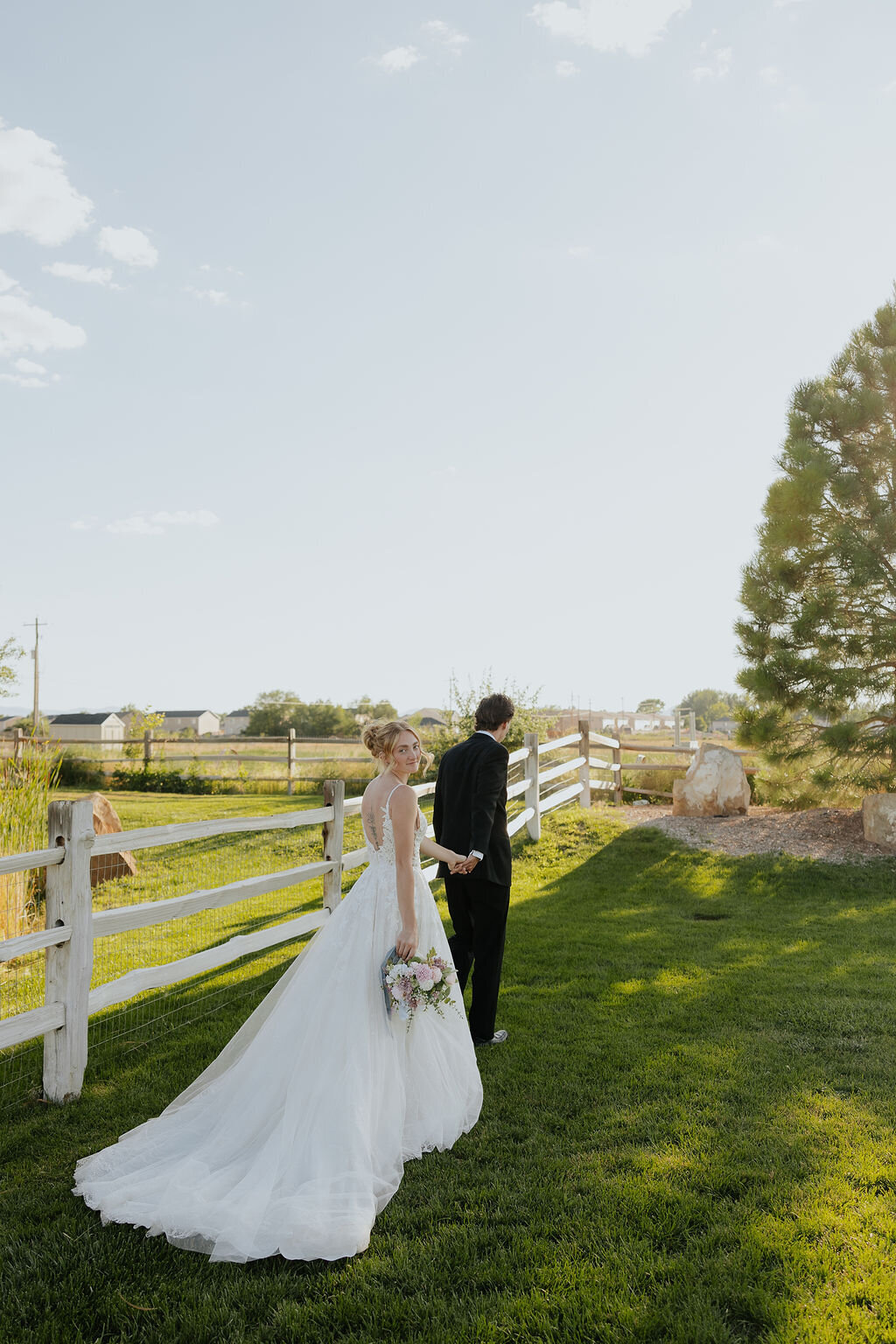 Bride and groom by the white fence on the lawn