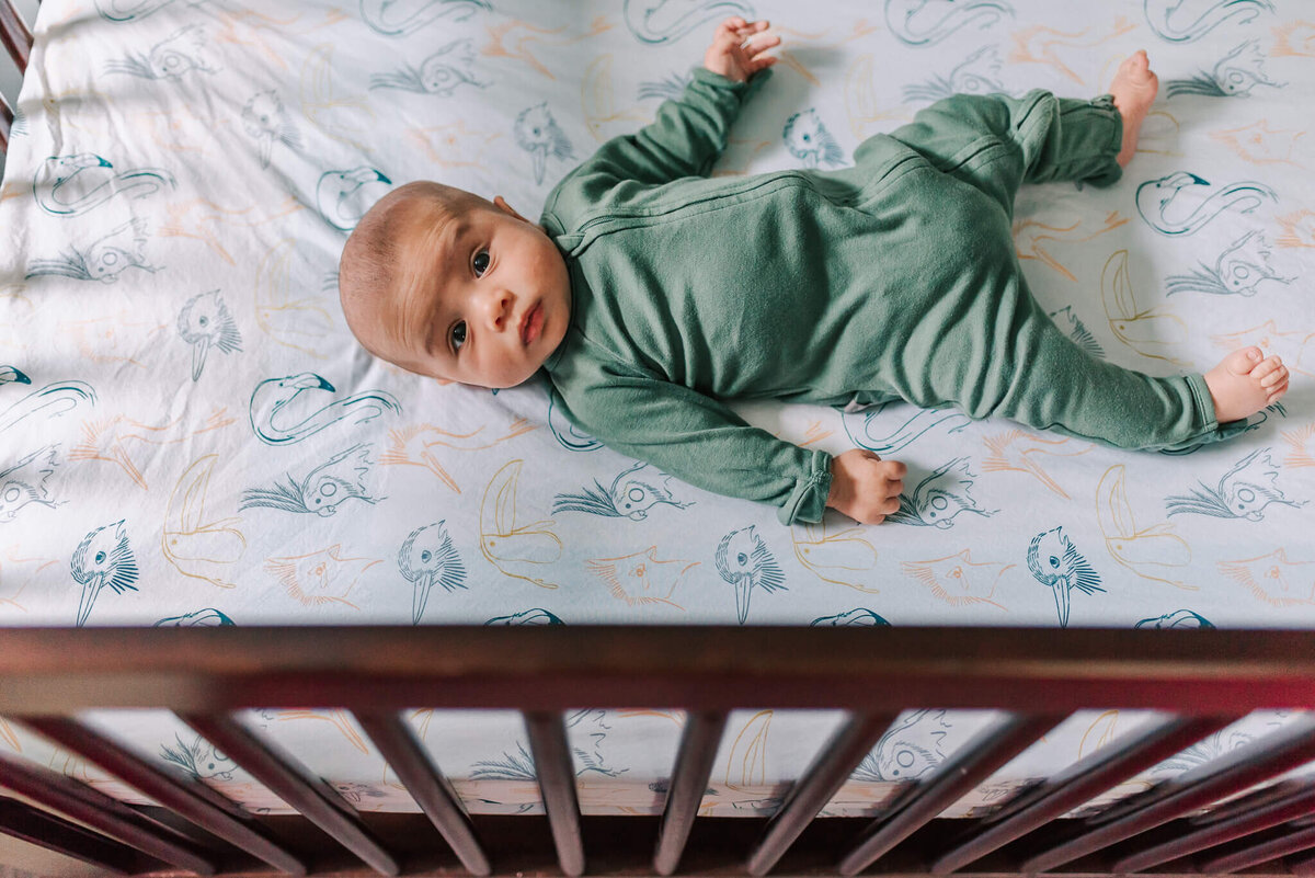 newborn photo of baby boy in his crib staring seriously at the camera