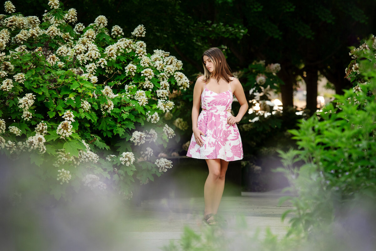 st-louis-senior-photographer-senior-girl-in-pink-floral-dress-on-with-trees-at-city-garden