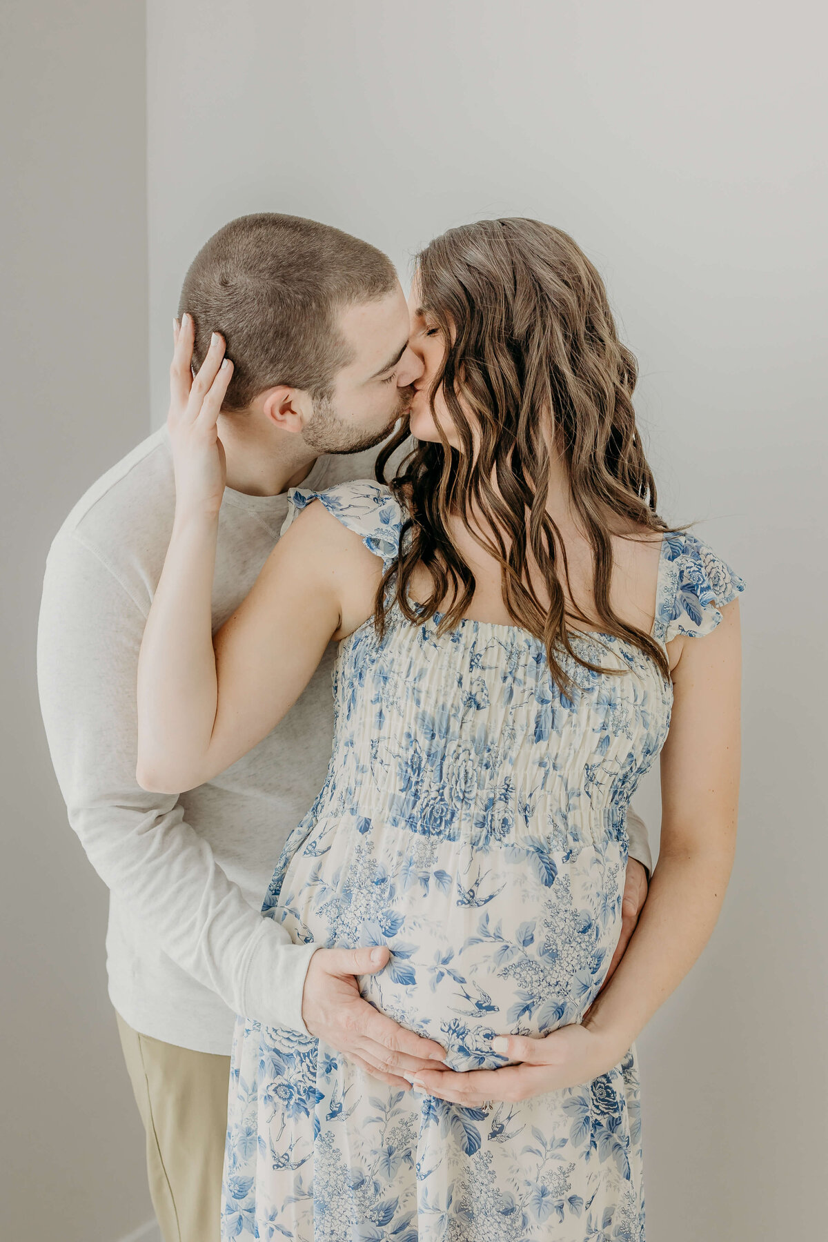 Mom and dad kissing while holding belly maternity photo near Eau Claire, WI