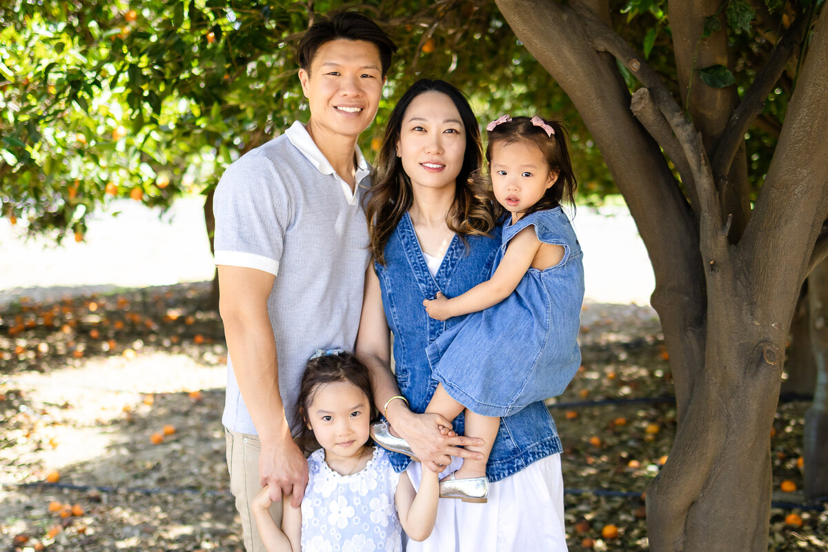 Mom and Dad sharing a warm hug with her two daughters children during a playful outdoor session – lifestyle family photography by Ellobelle Photography, San Francisco Peninsula