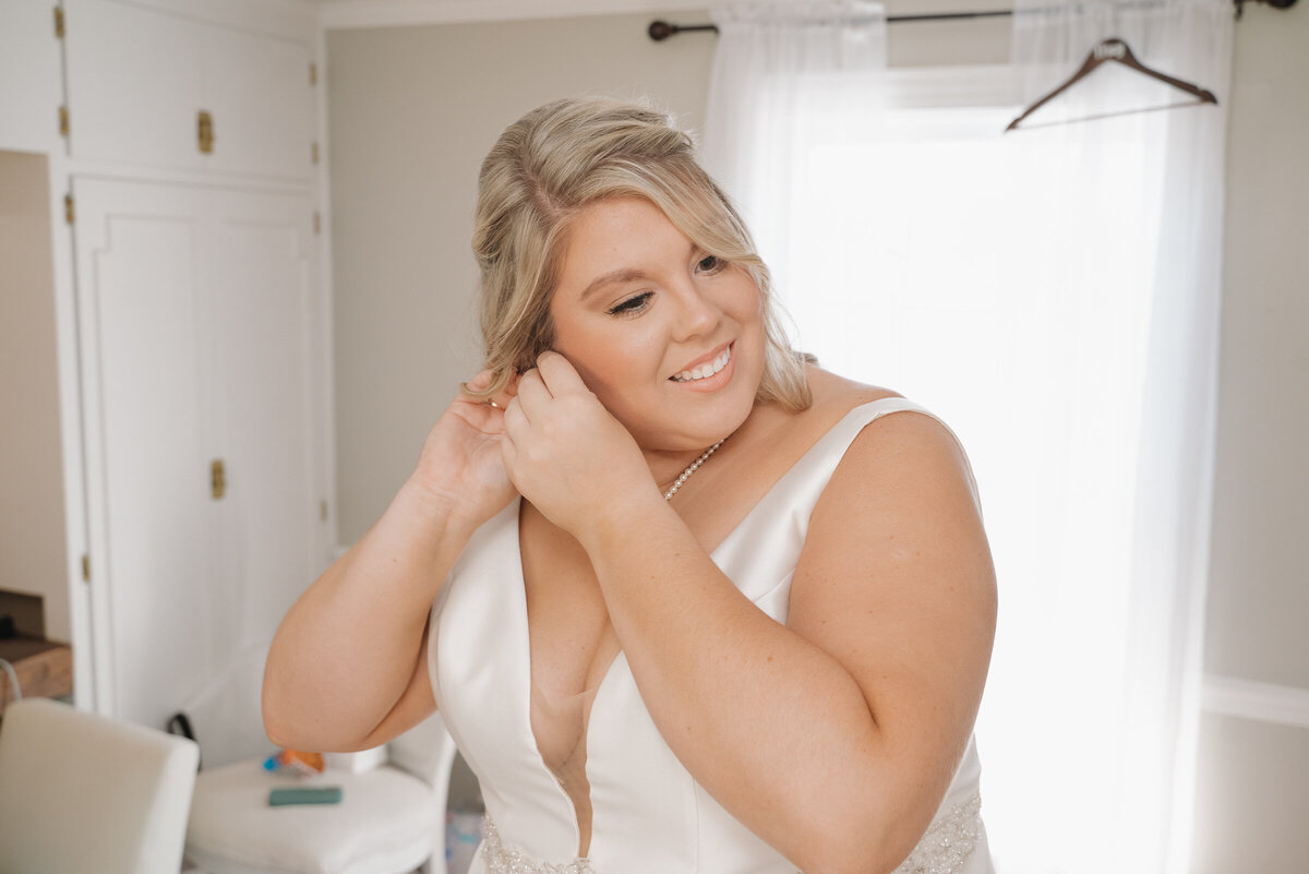 Bride putting on ear rings 