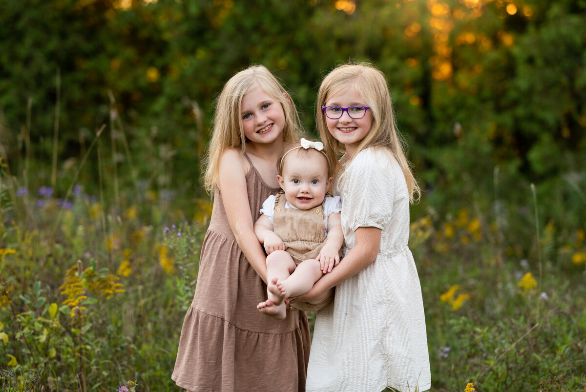 Twins holding their little sister in a field in Richmond